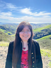a woman smiling in front of a hill